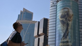 Turista observa imagem do troféu da Copa do Mundo do Catar projetada em prédio de Doha — Foto: Raul ARBOLEDA / AFP