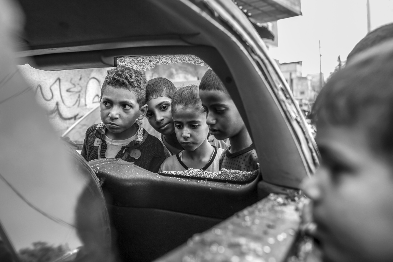 Crianças se reúnem em torno de um carro danificado por ataque aéreo israelense do lado de fora de uma escola em Khan Younis, Faixa de Gaza — Foto: Samar Abu Elouf/The New York Times