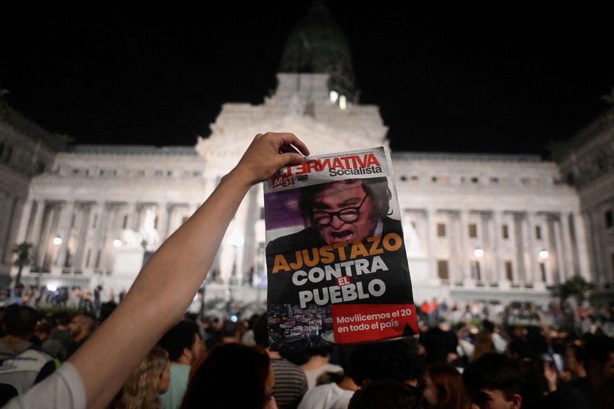 Manifestante segura panfleto com foto de Milei durante protesto contra o presidente