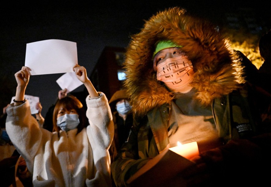 Manifestantes carregando cartaz em branco marcham em Pequim nesta segunda-feira