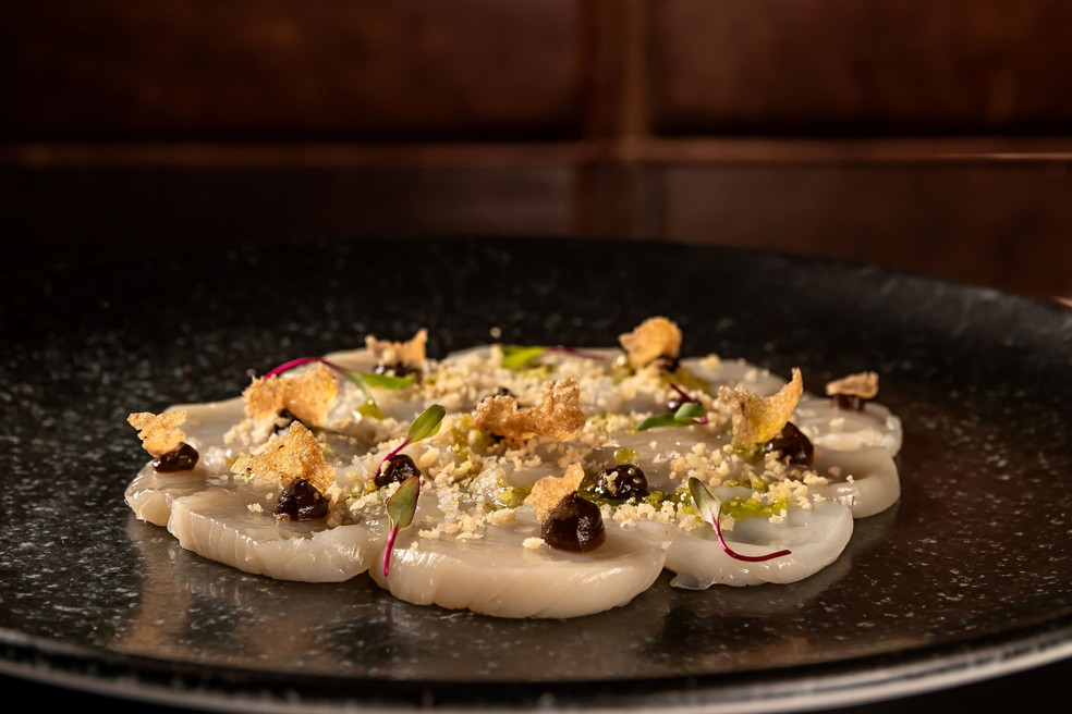 O crudo de vieiras, purê de alho negro e crocante de anchova — Foto: Divulgação / Foto de Alex Souto