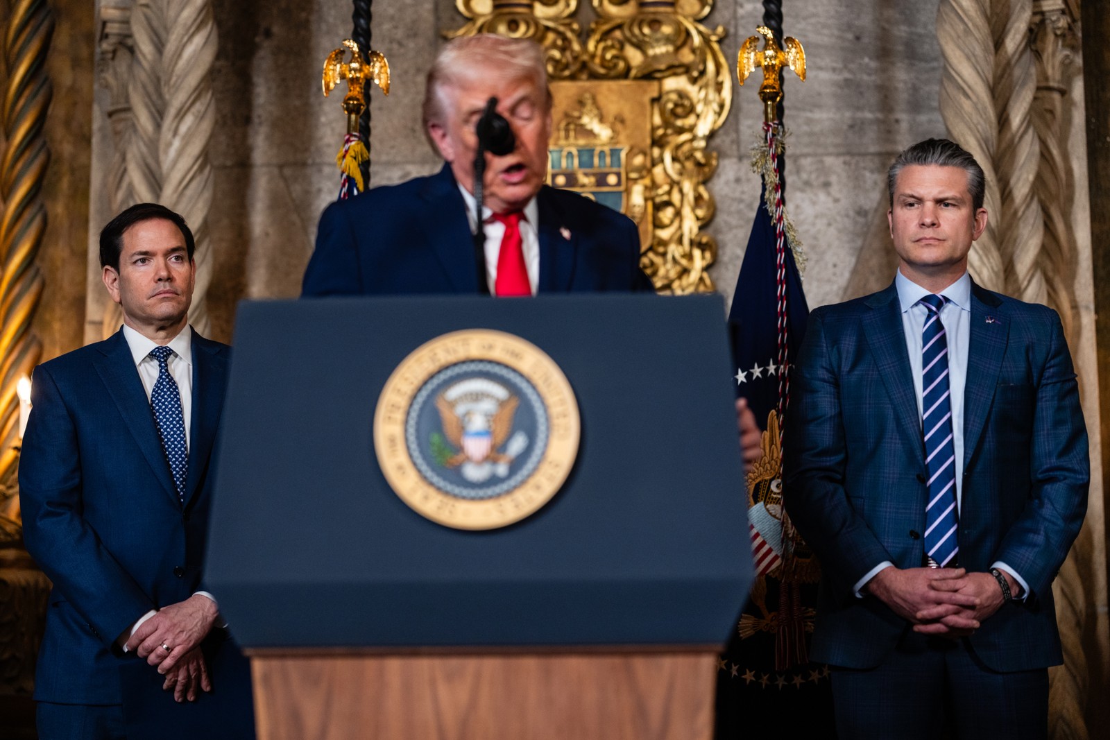 O secretário de Estado, Marco Rubio, e o secretário de Defesa, Pete Hegseth, estão atrás do presidente Donald Trump durante o anúncio de um plano para construir navios de guerra da “classe Trump”, em Mar-a-Lago. — Foto: Eric Lee / The New York Times