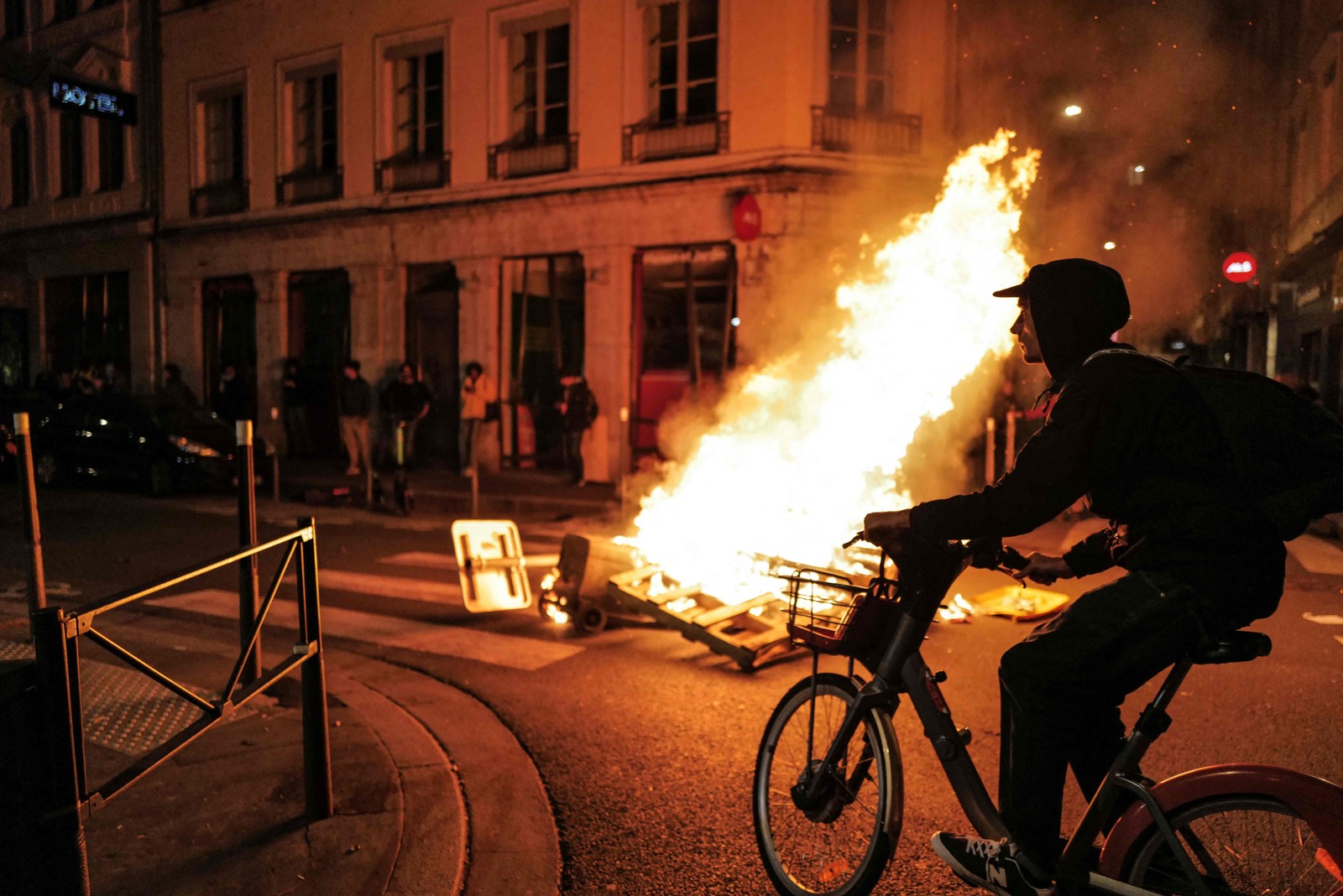 Ciclista passa por barricada em chamas durante uma manifestação em Lyon. — Foto: OLIVIER CHASSIGNOLE / AFP