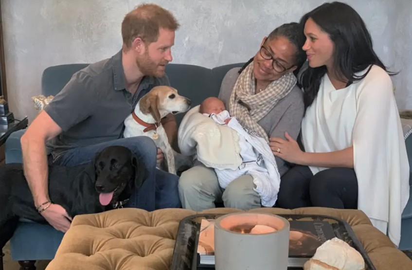 Doria Ragland, mãe de Meghan Markle, segura o neto Archie no colo, entre a filha e o genro, príncipe Harry, na sala de estar do Frogmore Cottage, no Reino Unido — Foto: Reprodução / Netflix