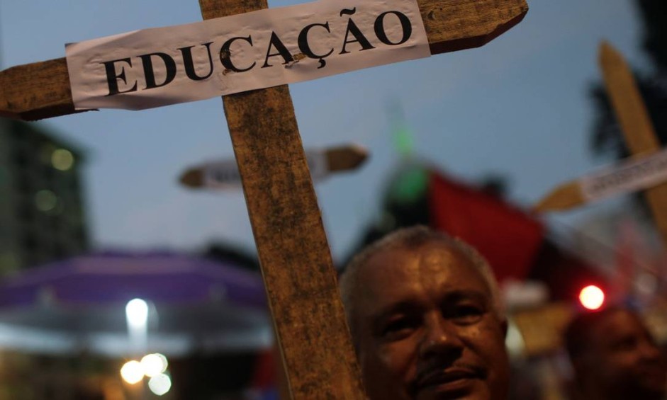 Um homem segura uma cruz com a placa "Educação" durante um protesto de estudantes contra cortes nos gastos federais no setor planejados pelo governo BolsonaroREUTERS