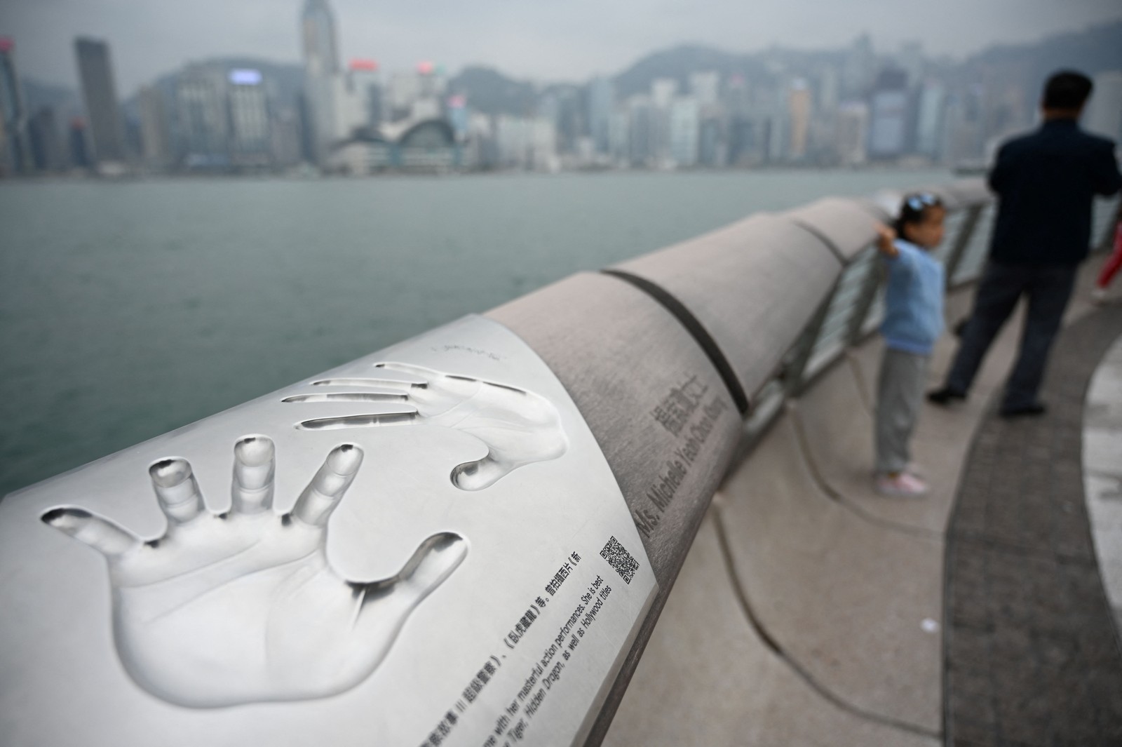 Turistas da China continental tiram fotos na Avenida das Estrelas ao lado das impressões das mãos da atriz Michelle Yeoh, em Hong Kong — Foto: Peter Parks/AFP