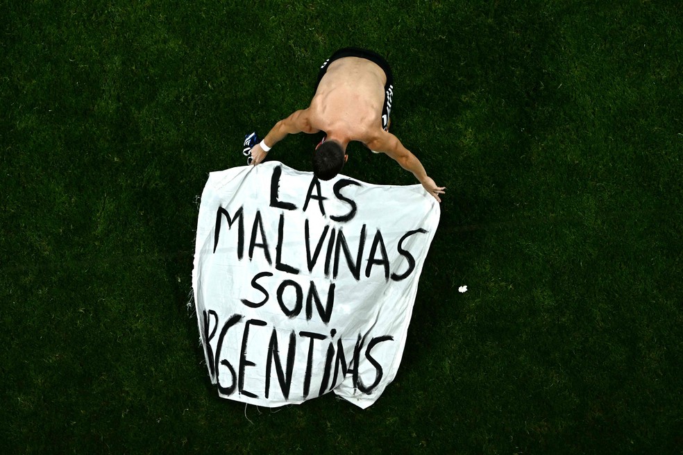 Giovani Lo Celso coloca faixa sobre Ilhas Malvinas no gramado do Estádio de Atlanta após vitória da Argentina — Foto: Jewel SAMAD / AFP