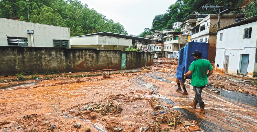 Homens carregam sofá no bairro Três Moinhos, um dos mais atingidos pelas chuvas em Juiz de Fora: seja por não saber se voltarão, seja pelo temor de saques, moradores estão recolhendo pertences