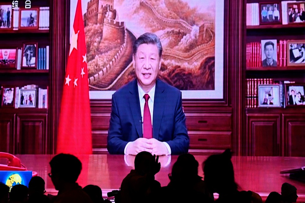 Pessoas jantam em um restaurante enquanto uma tela transmite o presidente da China, Xi Jinping, durante seu discurso de Ano Novo em Pequim, em 31 de dezembro de 2023 — Foto: PEDRO PARDO / AFP