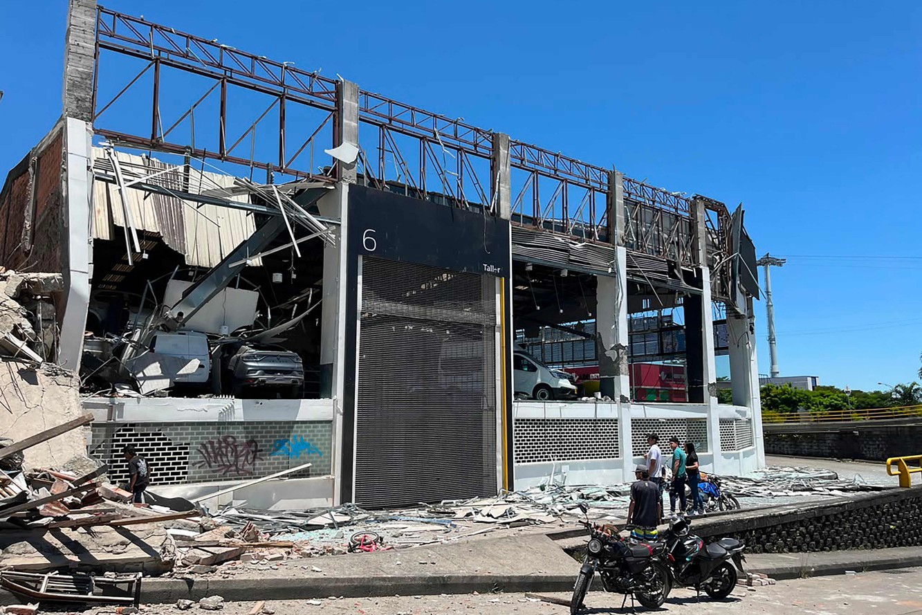 Pessoas observam uma concessionária de veículos danificada após um terremoto em Pereira, Colômbia. — Foto: Roberto Betancourt / AFP