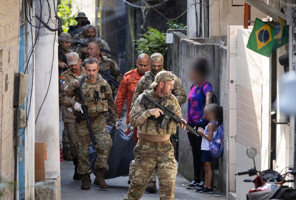 Adolescente cobre rosto de criança com a mão, durante retirada de cadáver em operação na Ladeira dos Tabajaras — Foto: Márcia Foletto / Agência O Globo / 15-04-2025