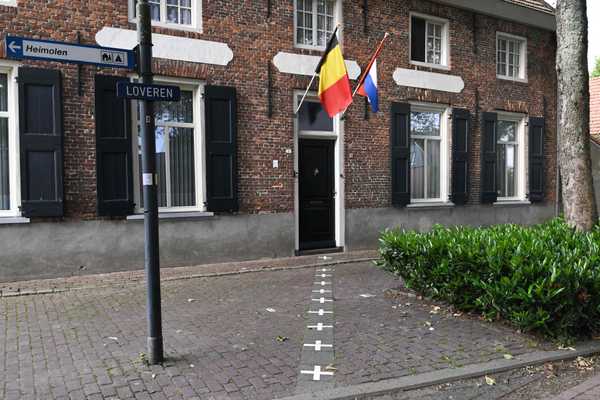 As bandeiras da Bélgica e dos Países Baixos ficam na entrada de um prédio localizado ao longo da fronteira