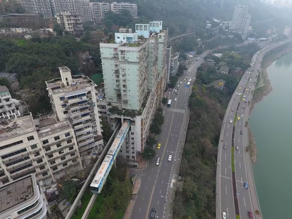 O trem passa por um edifício residencial sem interromper a vida cotidiana, um exemplo da harmonia entre a inovação urbana e a densidade populacional — Foto: La Nacion via Getty Images