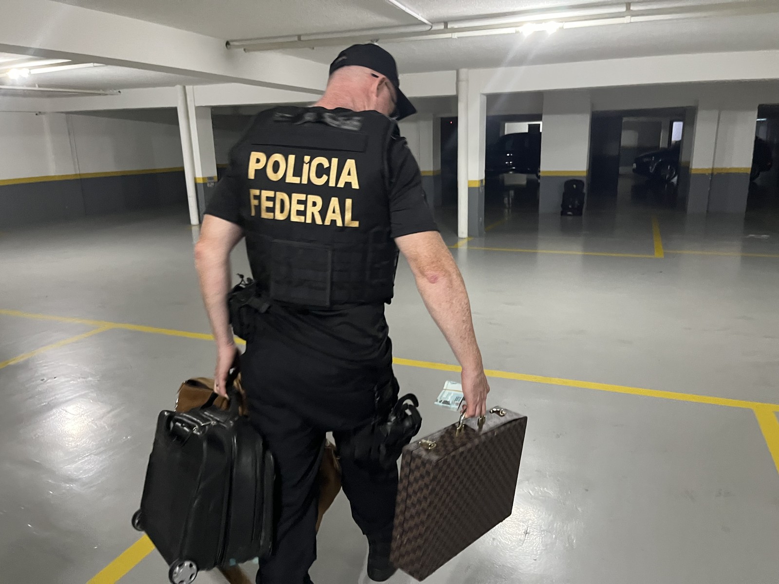 Agente carrega malas com material apreendido na casa de suspeito de tráfico internacional de drogas — Foto: Divulgação/PF