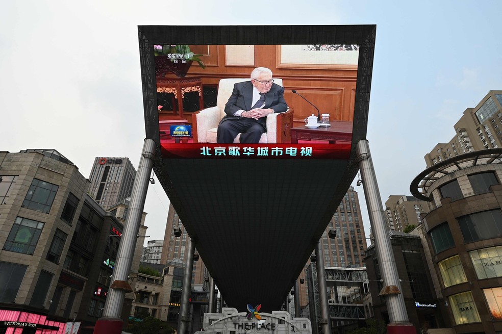 Telão fora de shopping center mostra noticiário com a cobertura da passagem de Henry Kissinger por Pequim. — Foto: Greg Baker/AFP
