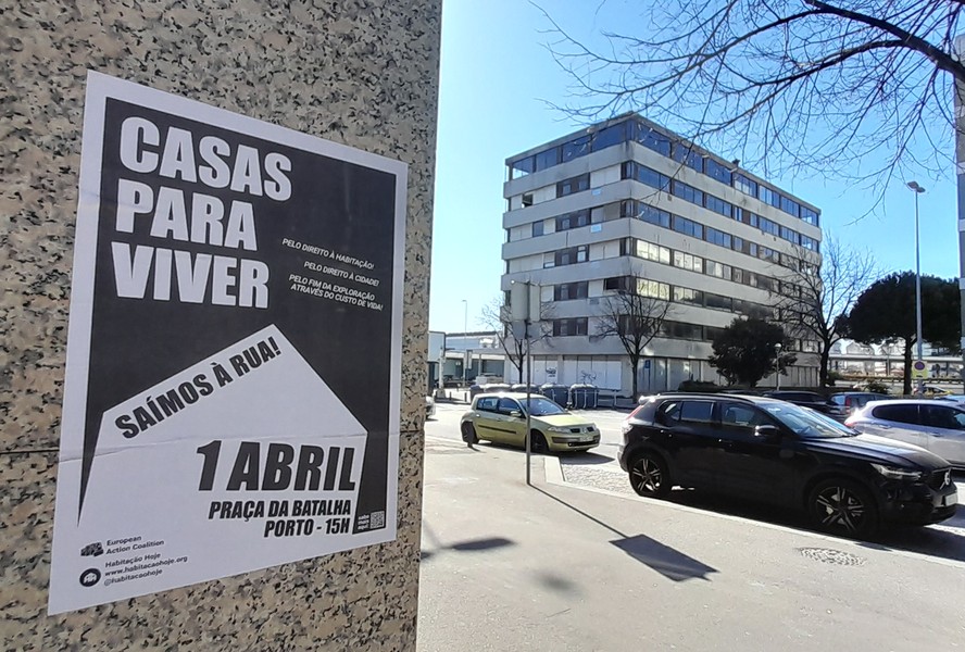 Cartaz de manifestação pelo direito à habitação. Ao fundo, o prédio devoluto no Porto