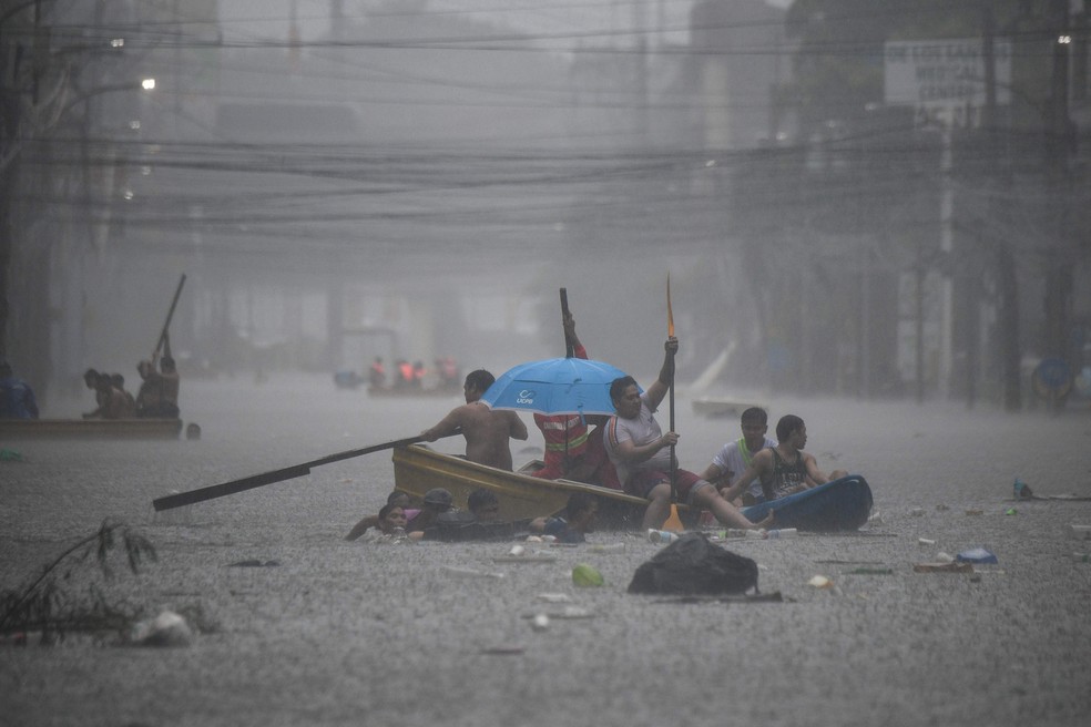 Equipes de resgate atravessam rua inundada em Manila — Foto: Ted ALJIBE / AFP