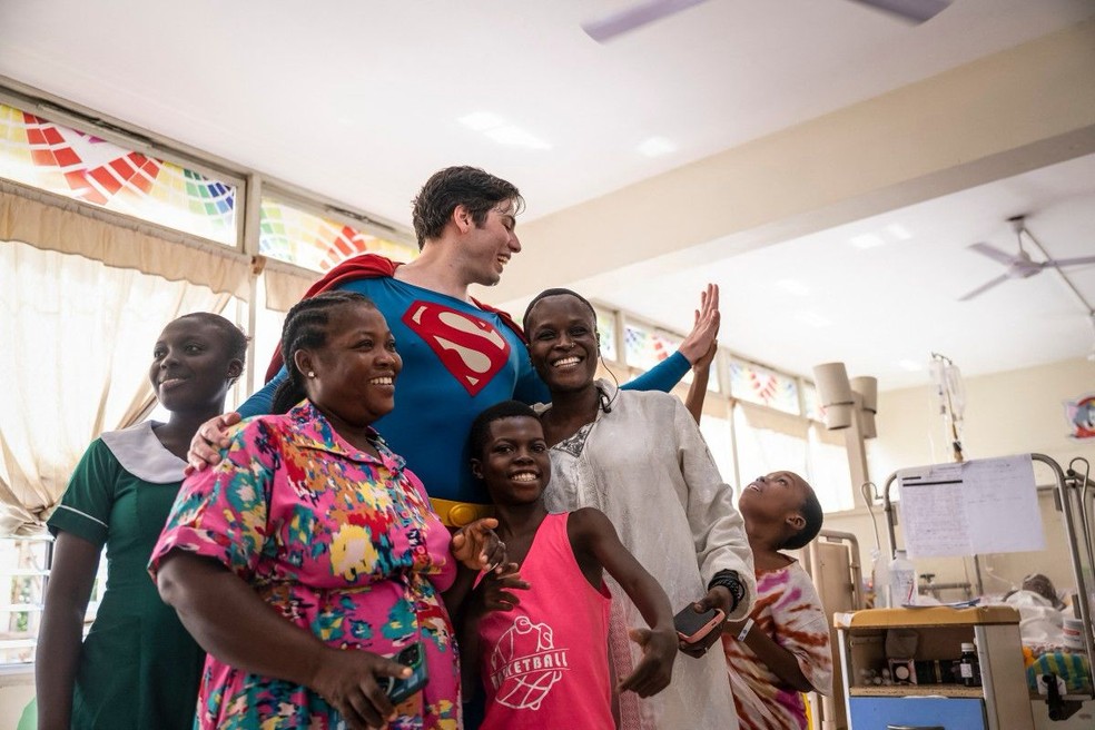 Leonardo Muiraert, known as Brazil's Superman, poses with patients and their families during a visit to Korle Bou University Hospital — Photo: CLAUDIA LACAVE / AFP