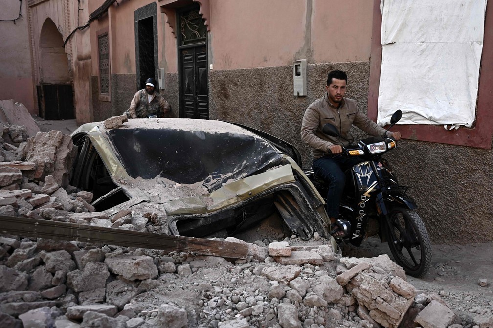 Motociclista passa por escombros no bairro antigo de Marrakech — Foto: Foto de Philippe Lopez/AFP
