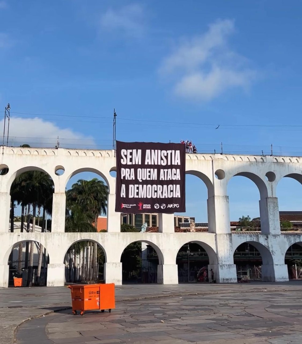 Militantes do MTST erguem bandeira contra PL da anistia nos Arcos da Lapa; agentes da PM removeram o símbolo em seguida — Foto: Reprodução/Redes sociais