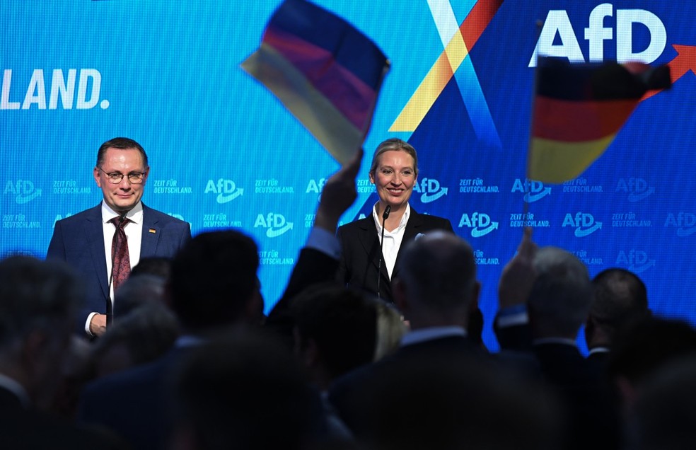 A co-líder do partido de extrema-direita AfD e candidata a chanceler Alice Weidel e o co-líder do partido Tino Chrupalla comemoram com membros do partido durante as eleições em Berlim — Foto: RALF HIRSCHBERGER / AFP