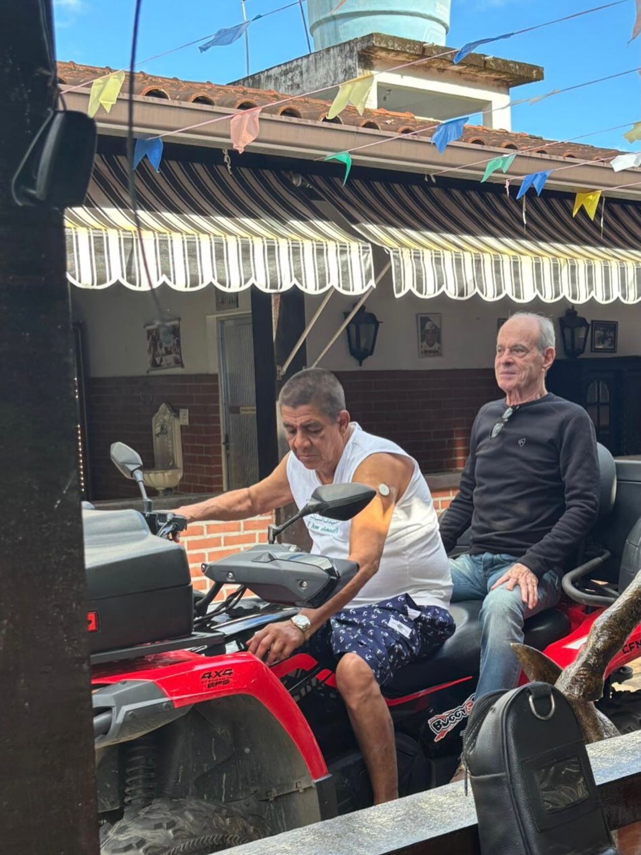Na carona de Zeca Pagodinho, Benedita da Silva anda de quadriciclo durante visita a Xerém