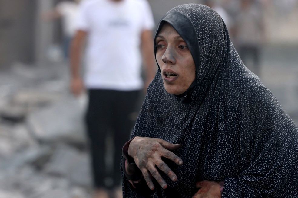 Mulher palestina coberta em poeira e fuligem aps bombardeio de Israel  Foto: Mohammed Abed/AFP