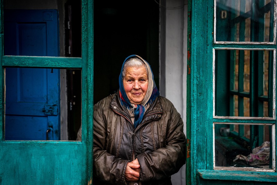 Mulher em frente a sua casa sem janelas após um bombardeio em Donetsk, na Ucrânia, em fevereiro