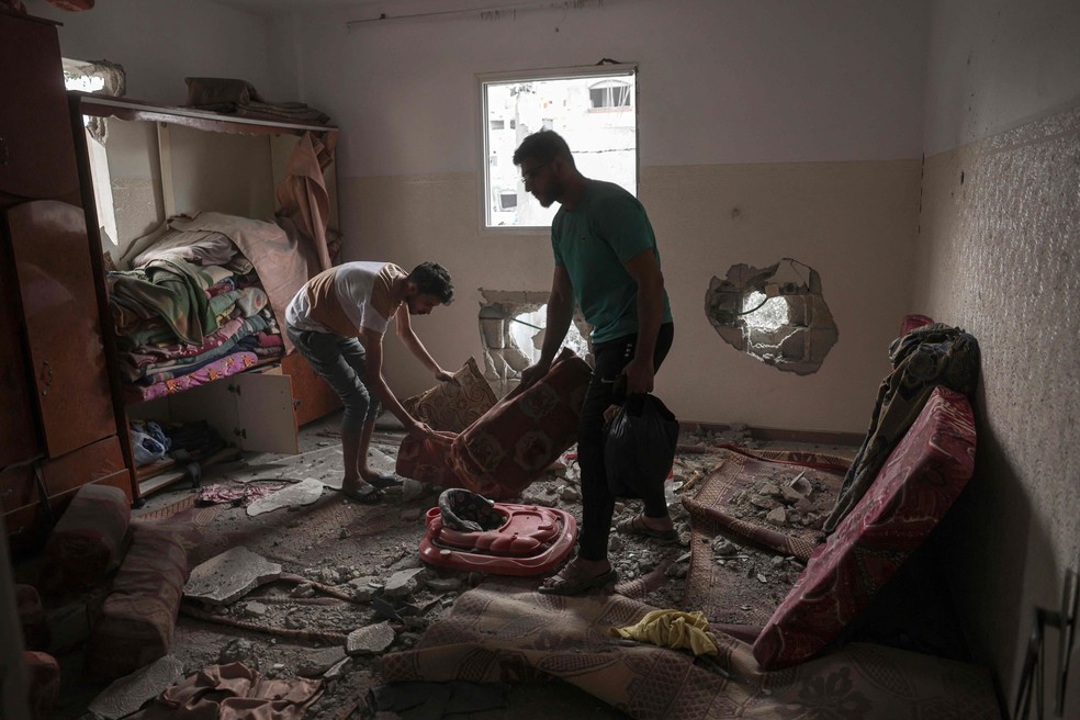 Famílias palestinas verificam o estado de suas casas após ataques de Israel — Foto: Mohammed Abed/AFP