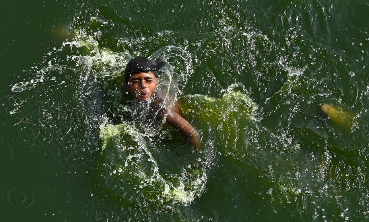 Um menino se refresca nas águas do rio Yamuna — Foto: SAJJAD HUSSAIN / AFP