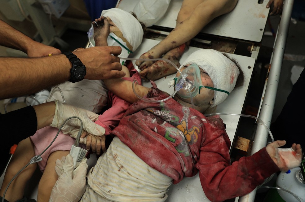 Duas crianças palestinas feridas em uma maca no Hospital Al-Aqsa, após o bombardeio israelense em Deir el-Balah, no centro da Faixa de Gaza, em 15 de novembro de 2023 — Foto: Bashar TALEB / AFP