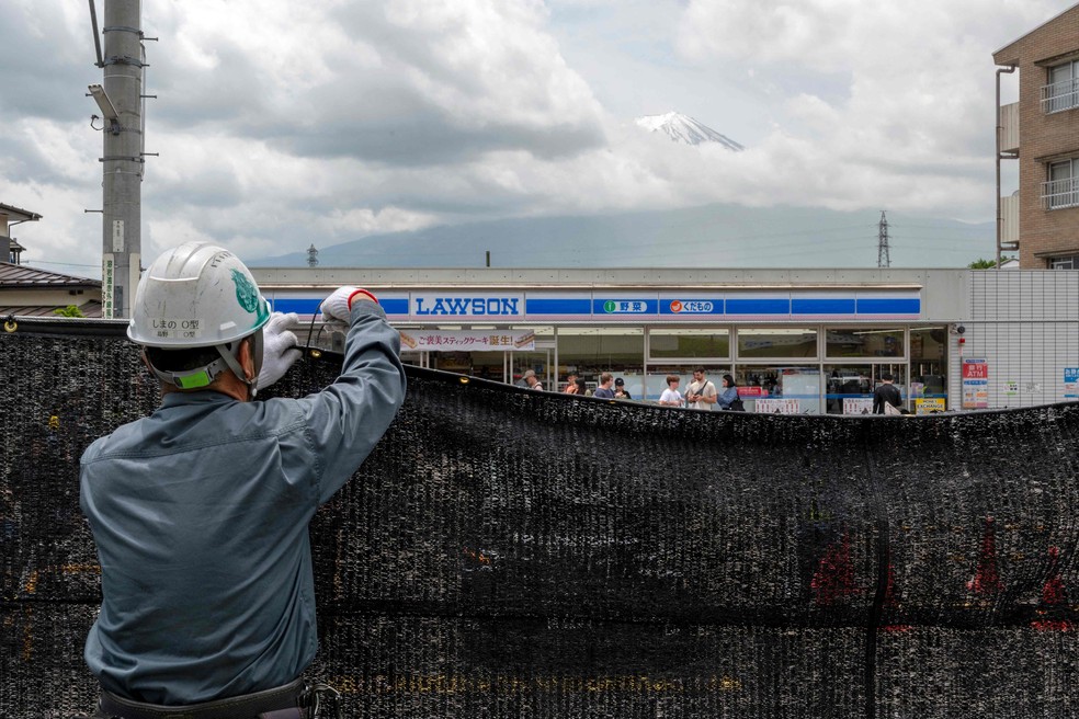 Funcionário instala tela para bloquear vista dos turistas do Monte Fuji — Foto: Kazuhiro NOGI / AFP