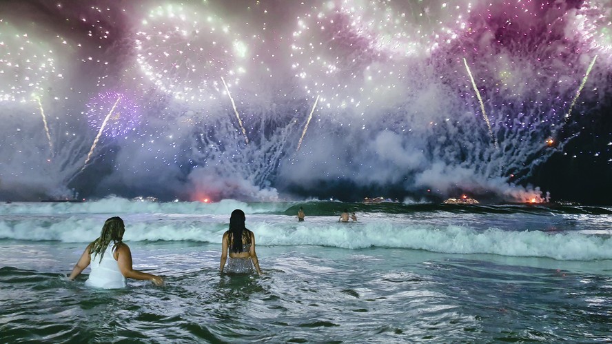 Pular sete ondas é um dos rituais mais comuns da virada de ano. Na foto, fogos iluminam a praia de Copacabana no Réveillon