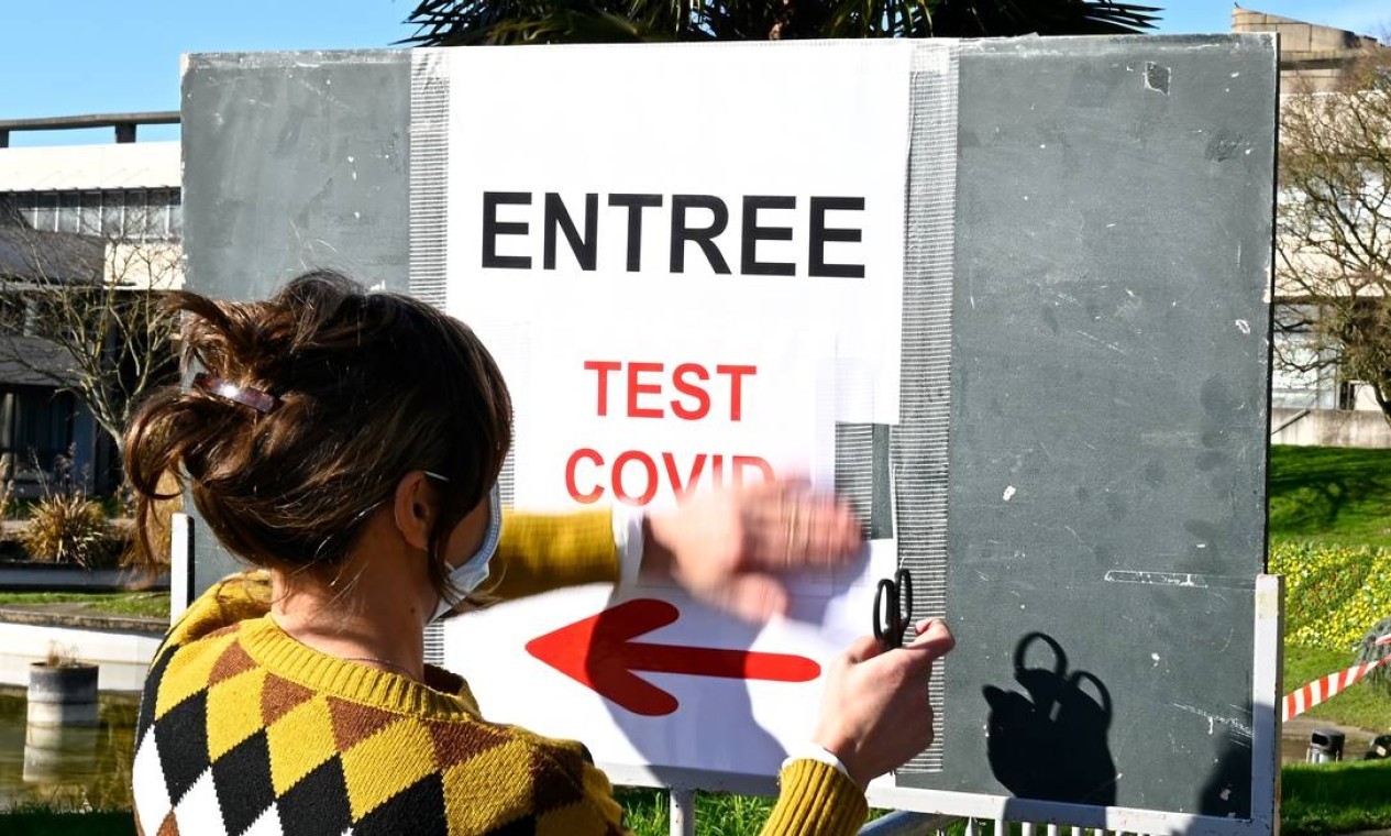 Um funcionário da Rennes 1 University cola um pôster para informar sobre uma campanha de teste da Covid-19 em um prédio da universidade em Rennes, oeste da França, em meio à crise ligada à pandemia Covid-19 causada pelo novo coronavírus — Foto: DAMIEN MEYER / AFP