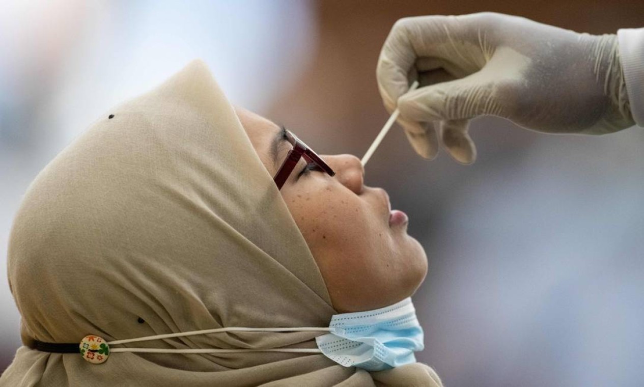 Trabalhador médico coleta amostra de swab de uma mulher para teste de coronavírus, em estrutura impreovisada em quadra de badminton, em Petaling Jaya, perto de Kuala Lumpur, capital da Malásia — Foto: MOHD RASFAN / AFP