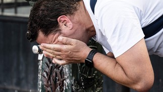 Homem esfria o rosto com água de uma fonte em Paris  — Foto: BERTRAND GUAY / AFP