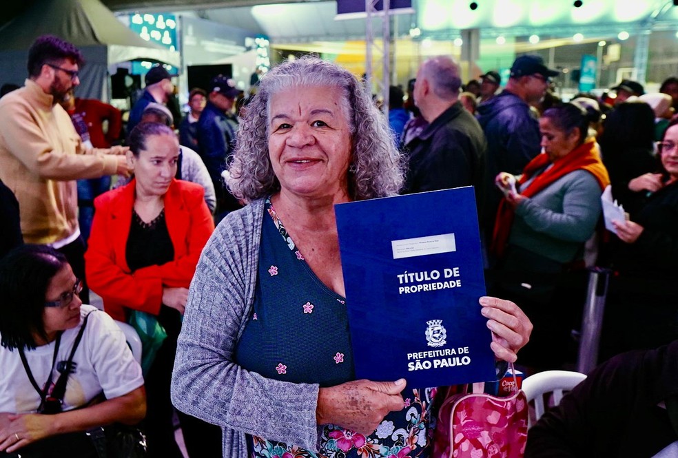 Beneficiária do programa Escritura na Mão recebe o título definitivo do imóvel, garantindo segurança jurídica e o reconhecimento oficial da propriedade — Foto: Sergio Arzaghi/PrefSP/Divulgação