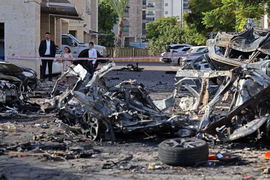 Moradores observam os destroços de veículos destruídos em Ashkelon após um ataque de foguete da Faixa de Gaza ao sul de Israel em 7 de outubro de 2023