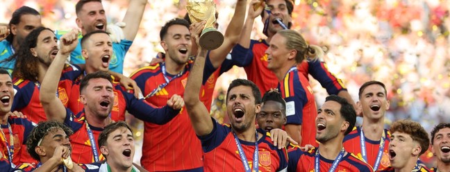 O meio-campista espanhol número 16, Rodri, ergue o troféu com seus companheiros de equipe após a vitória na final da Copa do Mundo de 2026 entre Espanha e Argentina — Foto: JUAN MABROMATA / AFP