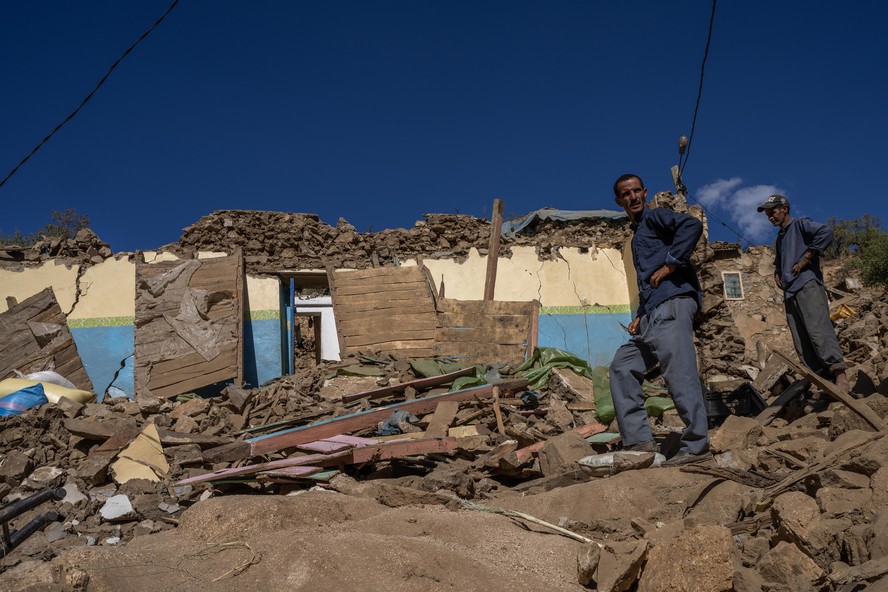 Brahim Bel Haj (à esquerda) e seu irmão Mohammed ao lado dos destroços da casa da família, no vilarejo de Ida Um Dostadud, destruída no terremoto que atingiu o Marrocos