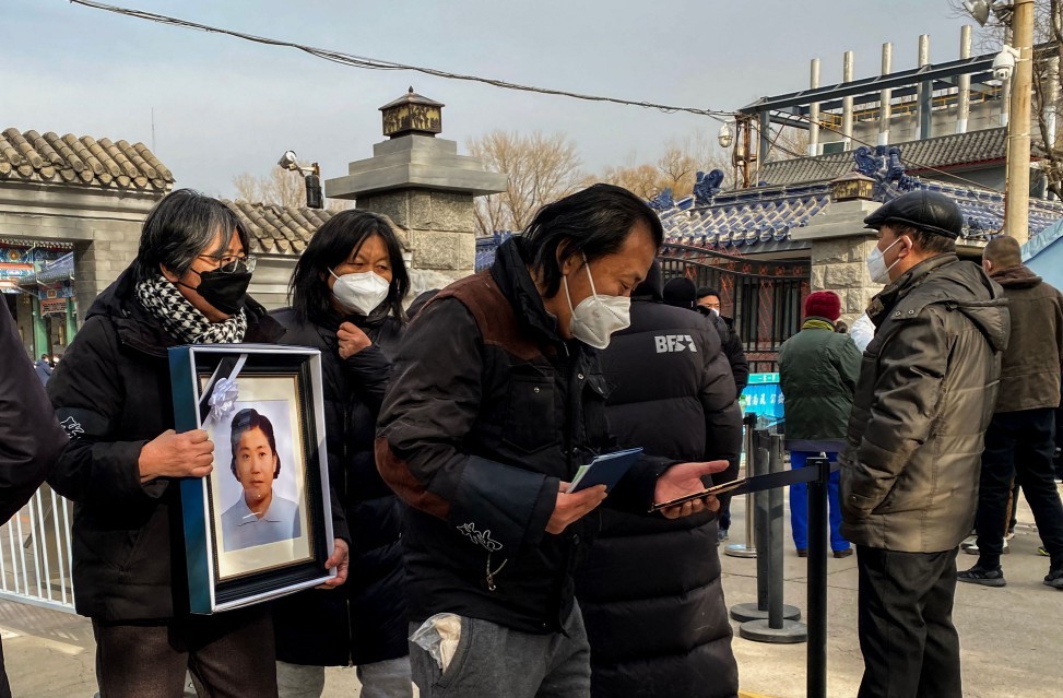 Mulher carrega foto de parente morto por Covid-19 em crematório de Pequim  — Foto: Noel Celis / AFP