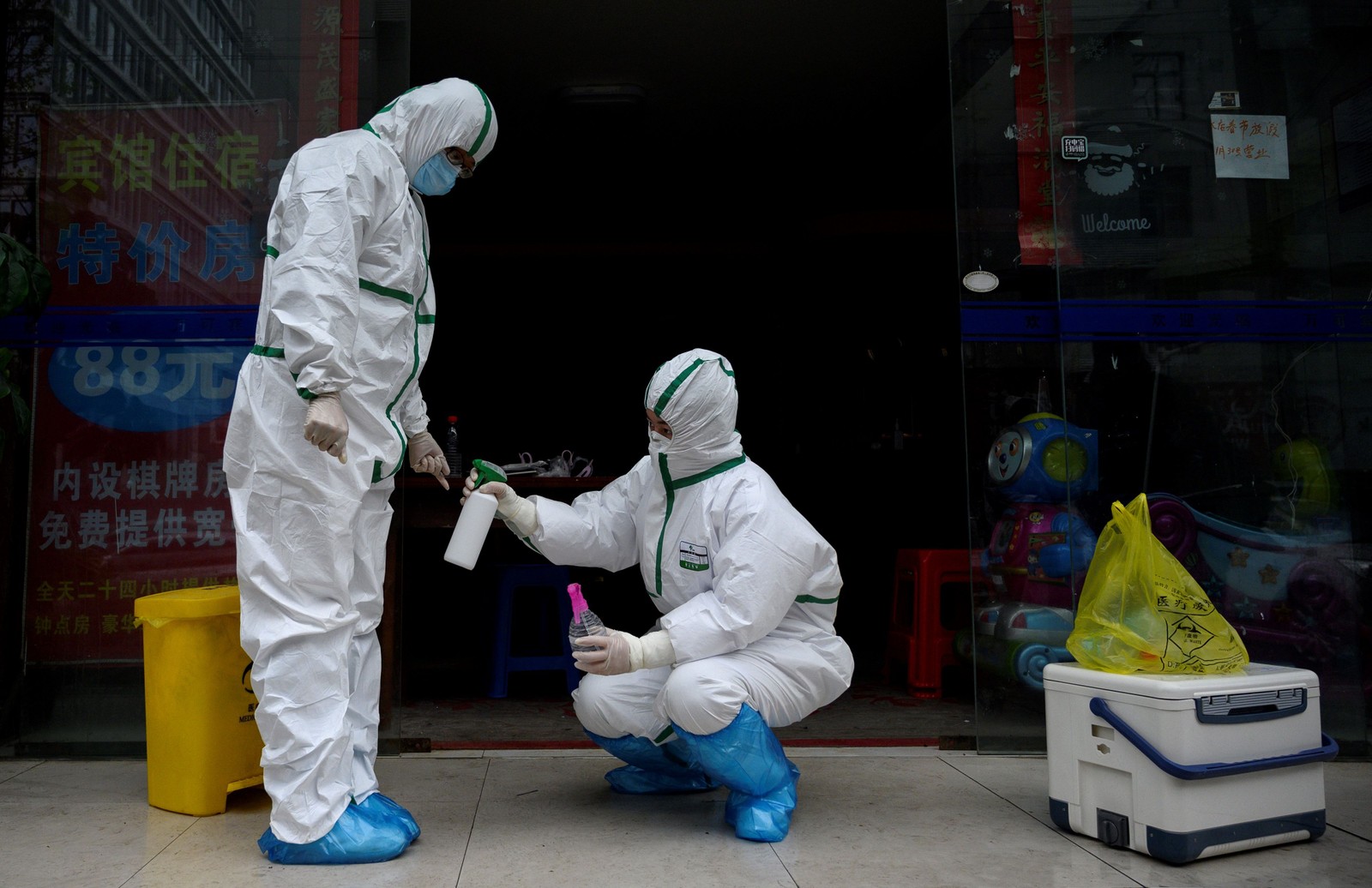 Médico em traje de proteção desinfeta colega em clínica de teste para Covid-19 em Wuhan, na China — Foto: Noel Celis / AFP