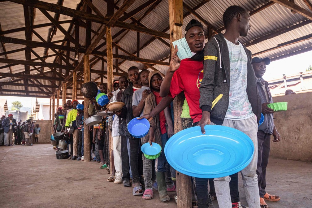 Milhares de pessoas que vivem perto da fronteira leste da RDC com Uganda fogem continuamente de suas casas para a Uganda, após ataques de insurgentes — Foto: BADRU KATUMBA / AFP