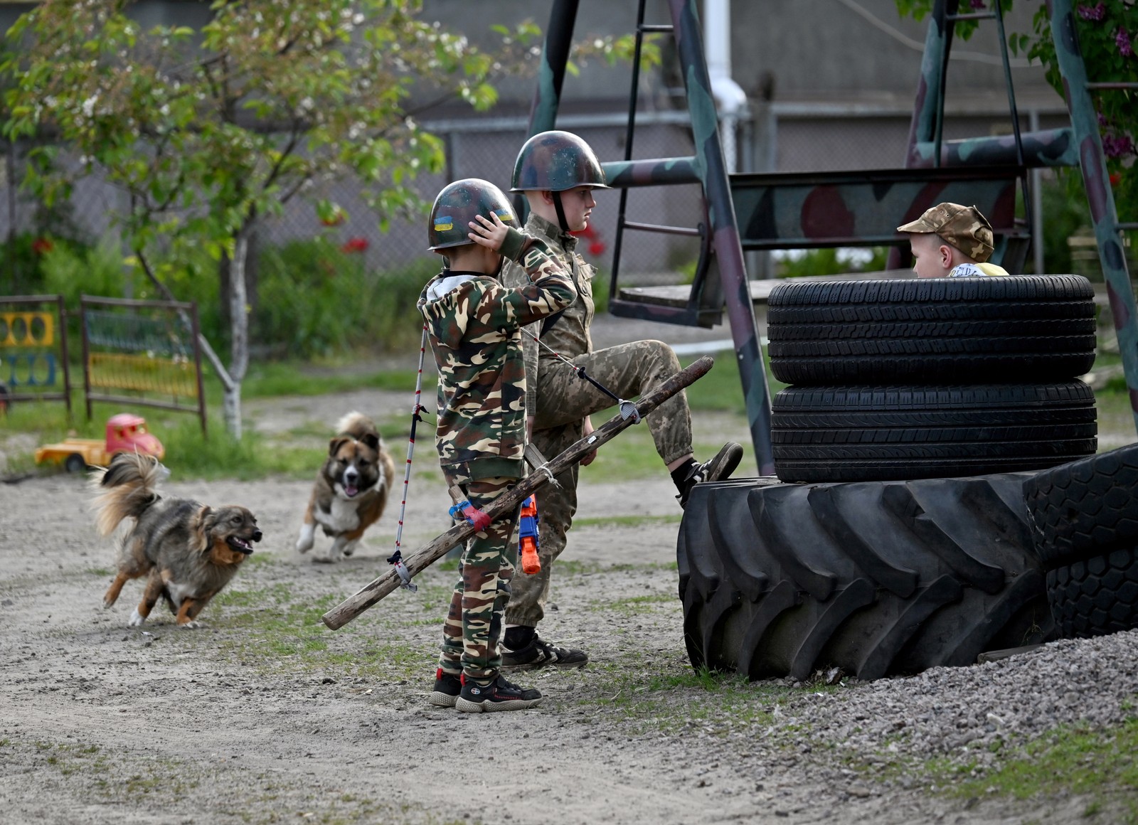 Meninos usam roupas camufladas e armas de plástico para emular guerra em brincadeiras — Foto: Sergei Supinsky/AFP