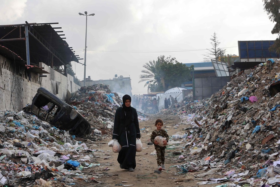 Palestinos deslocados pela guerra em Gaza se deslocam para acampamento montado perto de aterro sanitário — Foto: Omar al-Qattaa/AFP