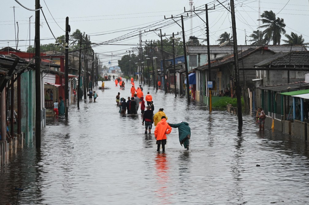 Pessoas caminham por uma rua inundada em Batabano, província de Mayabeque (Cuba), durante a passagem da tempestade tropical Idalia. — Foto: Yamil LAGE/AFP