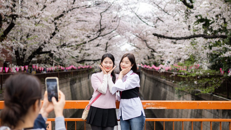 Jovens posam perto de cerejeiras em flor em Tóquio: desde março de 2023 não é mais obrigatório o uso de máscaras em locais públicos no Japão — Foto: Yuichi Yamazaki / AFP