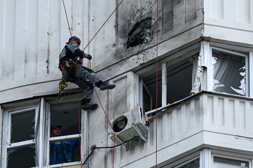 Especialista inspeciona fachada danificada de um prédio residencial após ataque de drone em Moscou