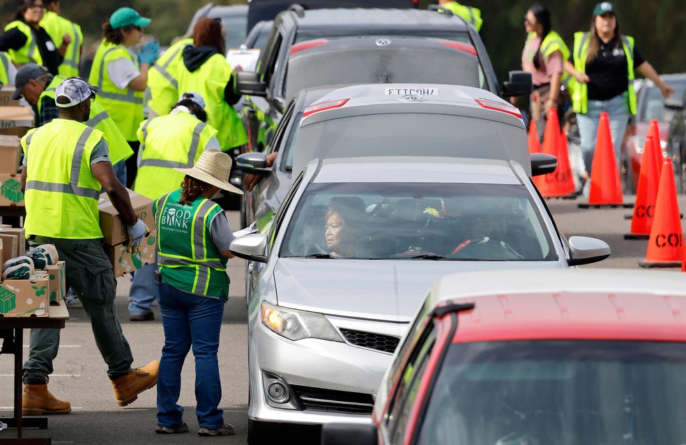 Trabalhadores e voluntários ajudam a distribuir cestas básicas para pessoas necessitadas em um grande evento de distribuição de alimentos no sistema drive-thru na Califórnia — Foto: Mario Tama/Getty Images/AFP