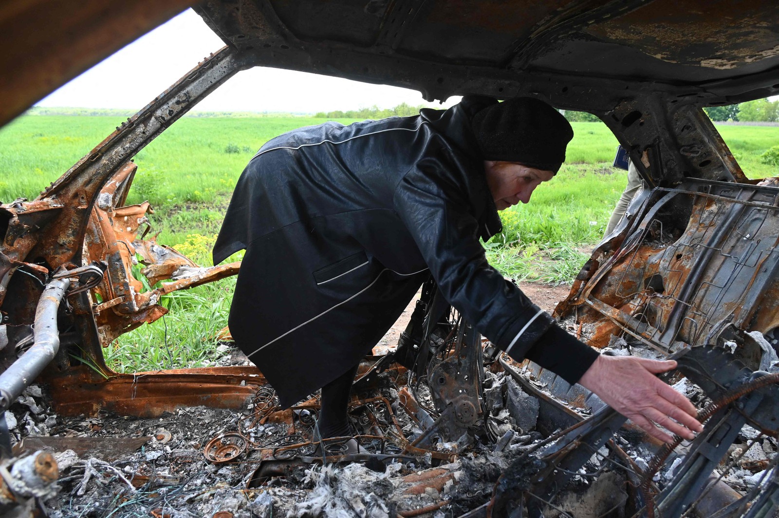 Olga Khomenko, 67 anos, procura os restos mortais de seu filho, um homem de 38 anos que morreu quando seu carro foi atingido por um tanque russo nos arredores da vila de Mala Rogan, perto de Kharkiv, leste da Ucrânia  — Foto: SERGEY BOBOK / AFP